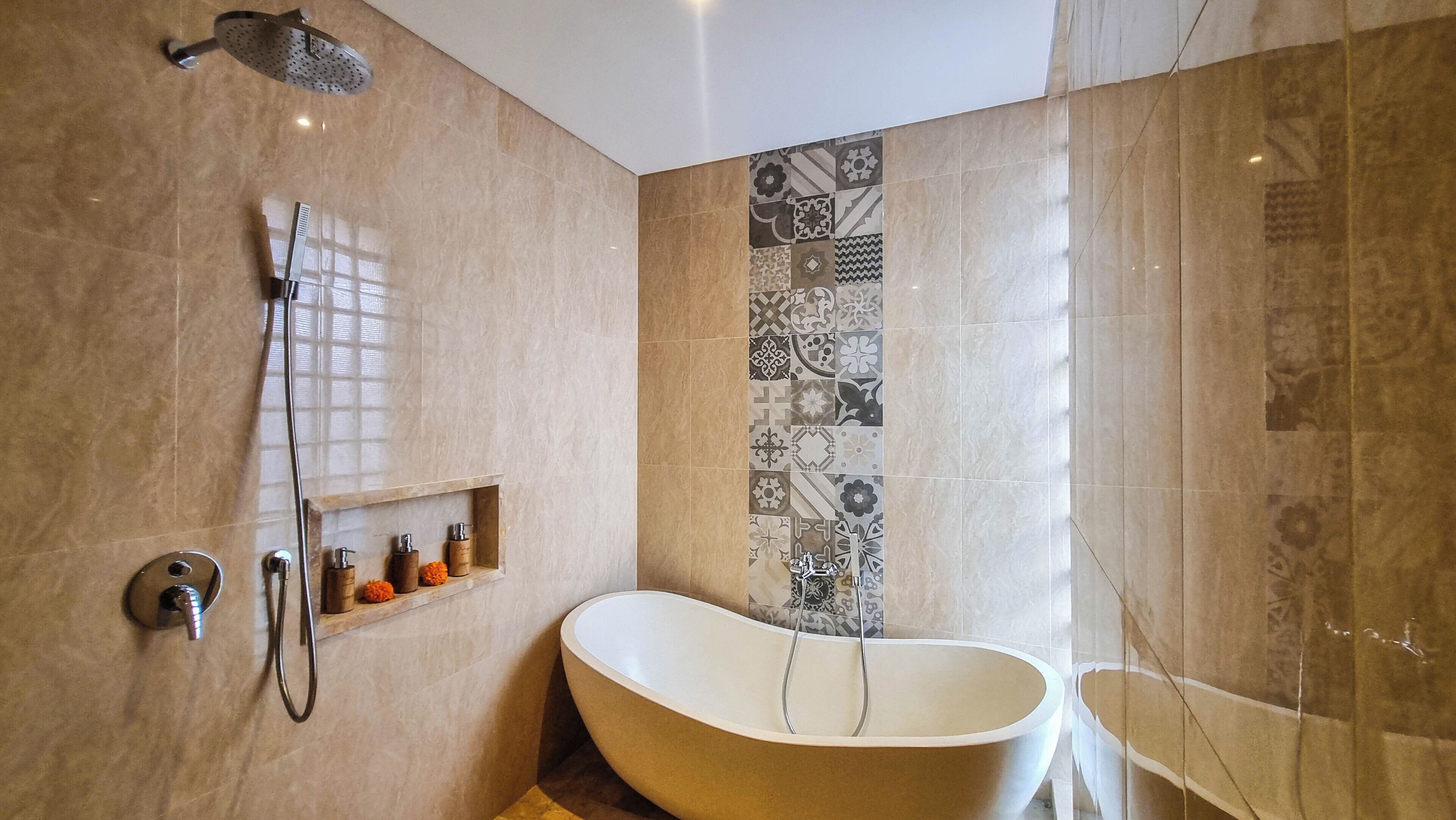 Een badkamer met een vrijstaand bad, een douchekop en een plank met toiletartikelen.