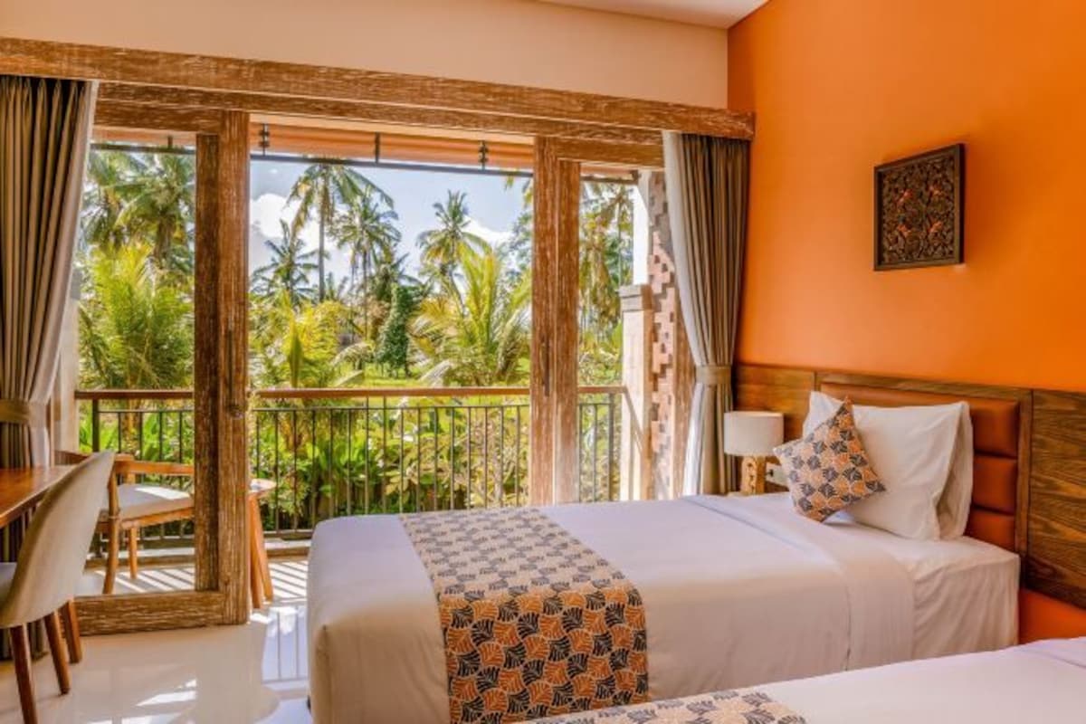 A hotel room with a balcony, a bed, a desk, and a chair.