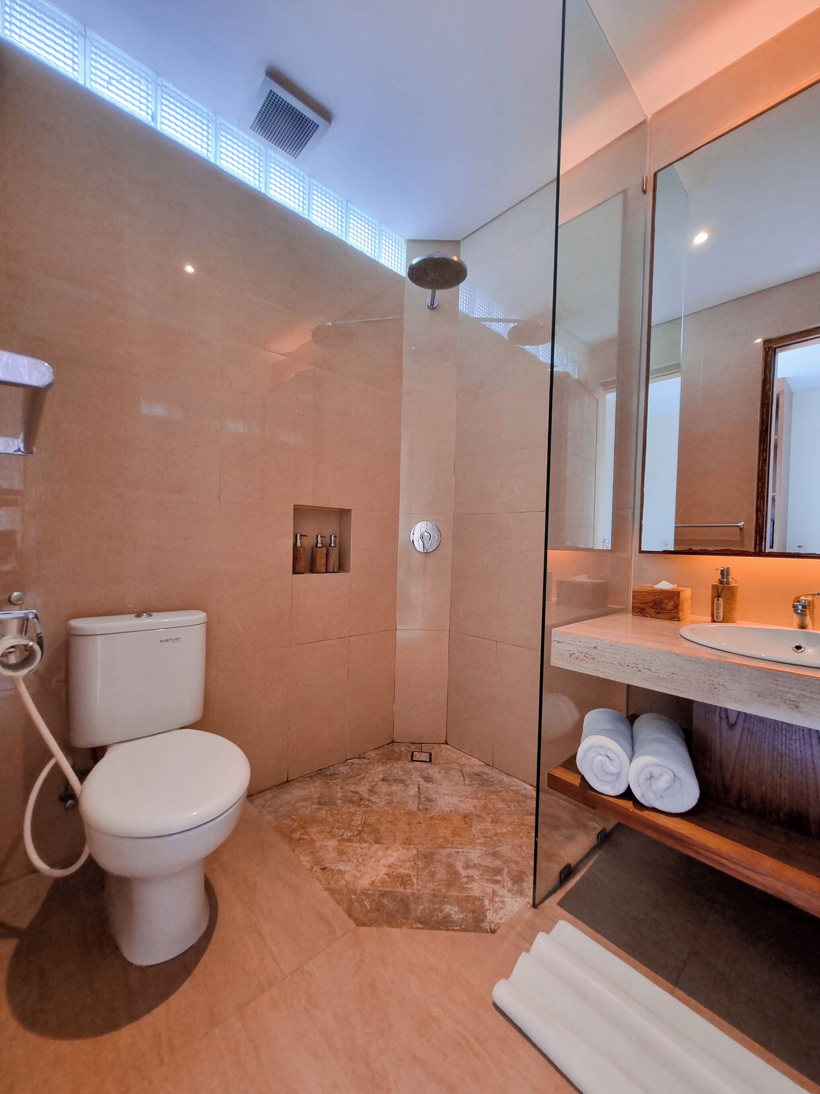 A modern bathroom with a glass-enclosed shower, a toilet, and a vanity with a mirror.