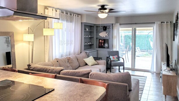 Una sala de estar moderna con sofá, mesa de comedor y ventilador de techo.