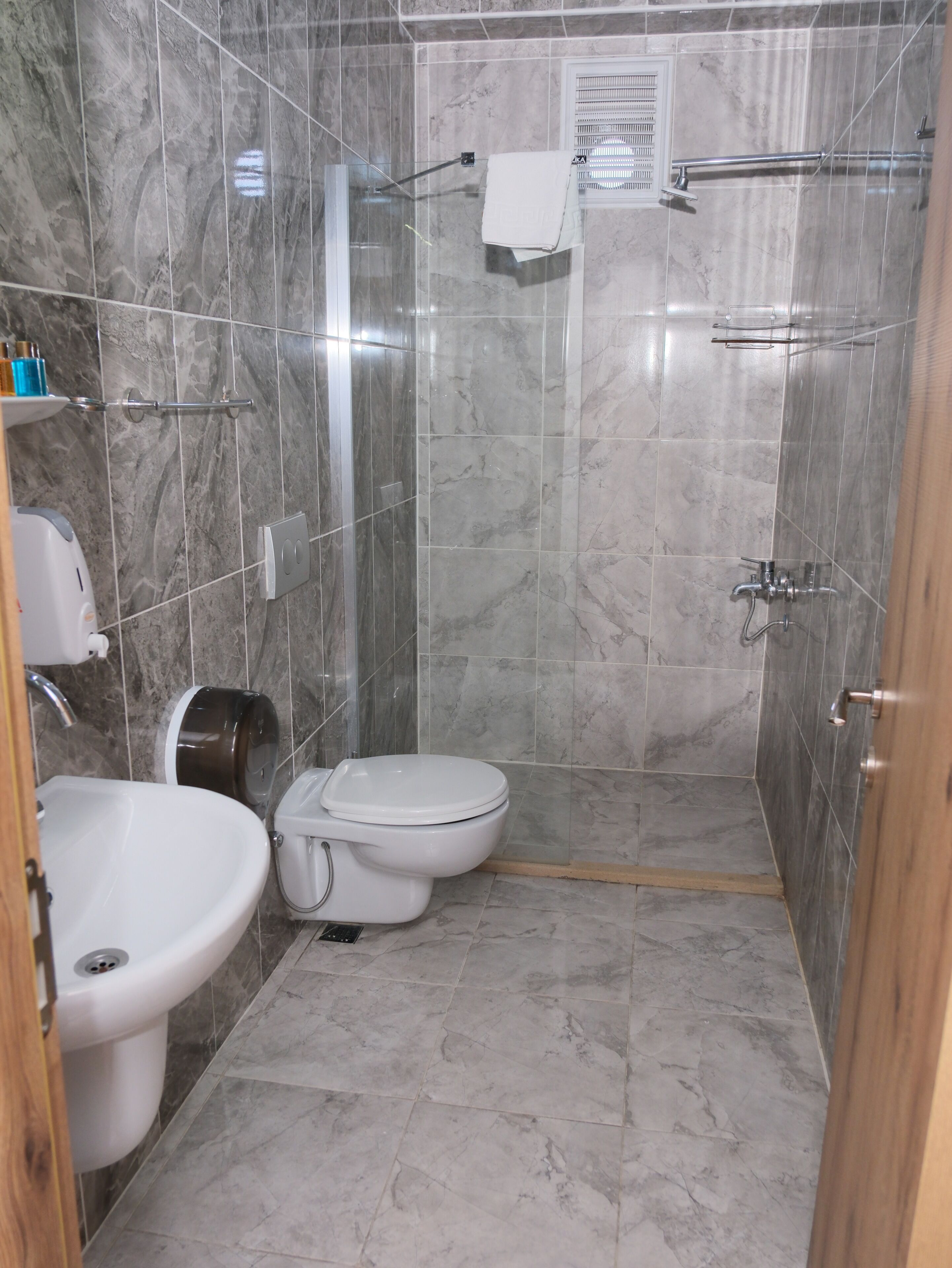 A bathroom with a toilet, sink, and shower area.
