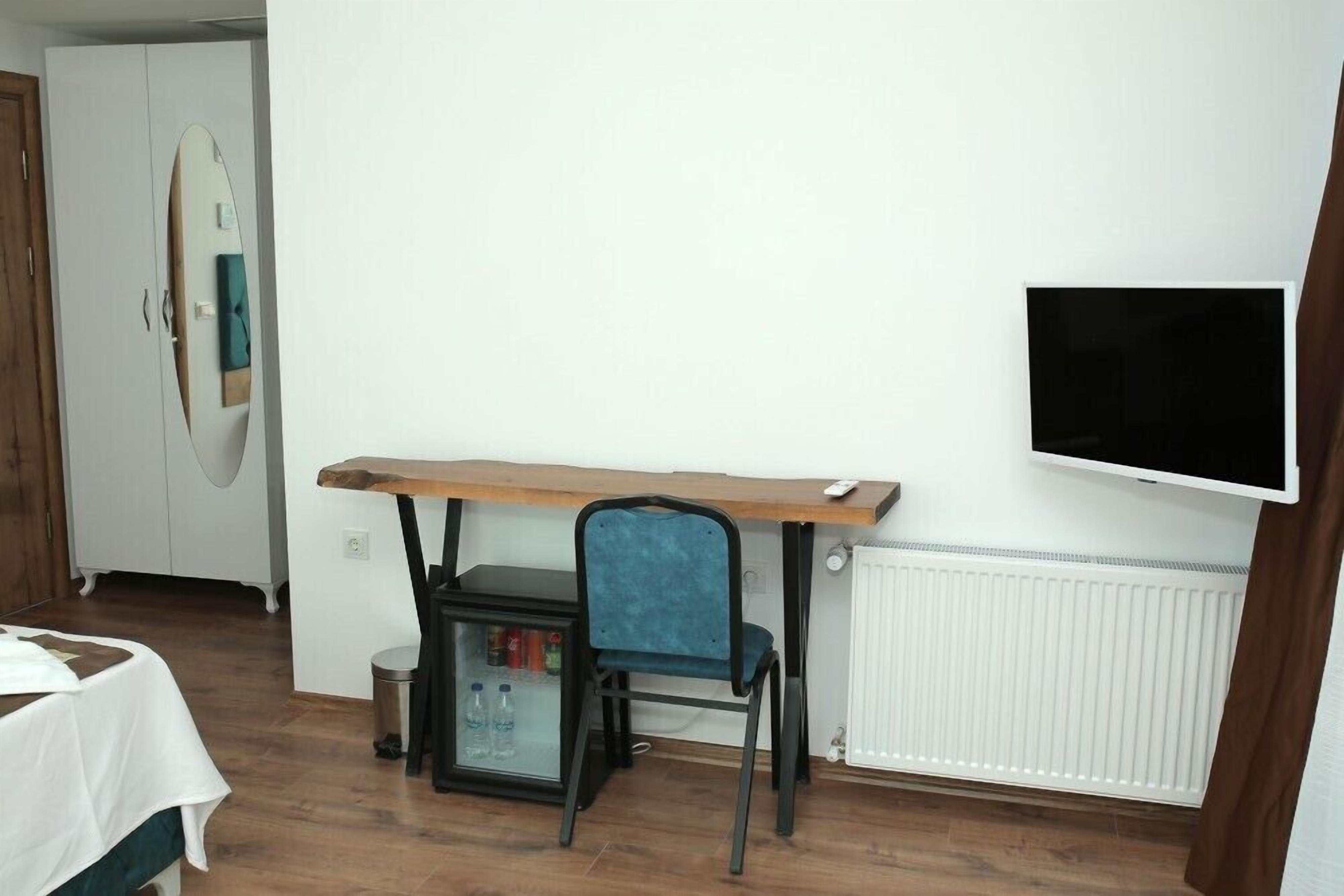 Una habitación con una cama, un escritorio y una silla, televisión y un radiador.