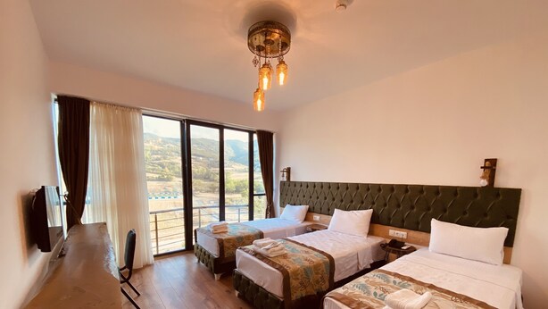 Habitación de hotel con dos camas, un escritorio y un ventanal con vistas al campo.