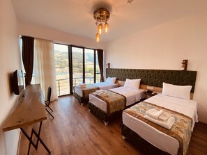 Une chambre d’hôtel avec deux lits, un bureau et une grande fenêtre donnant sur la campagne.