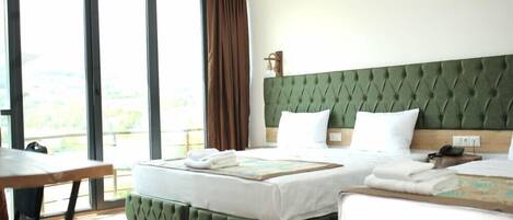 Habitación de hotel con dos camas, una mesa de comedor y ventanas grandes con cortinas.