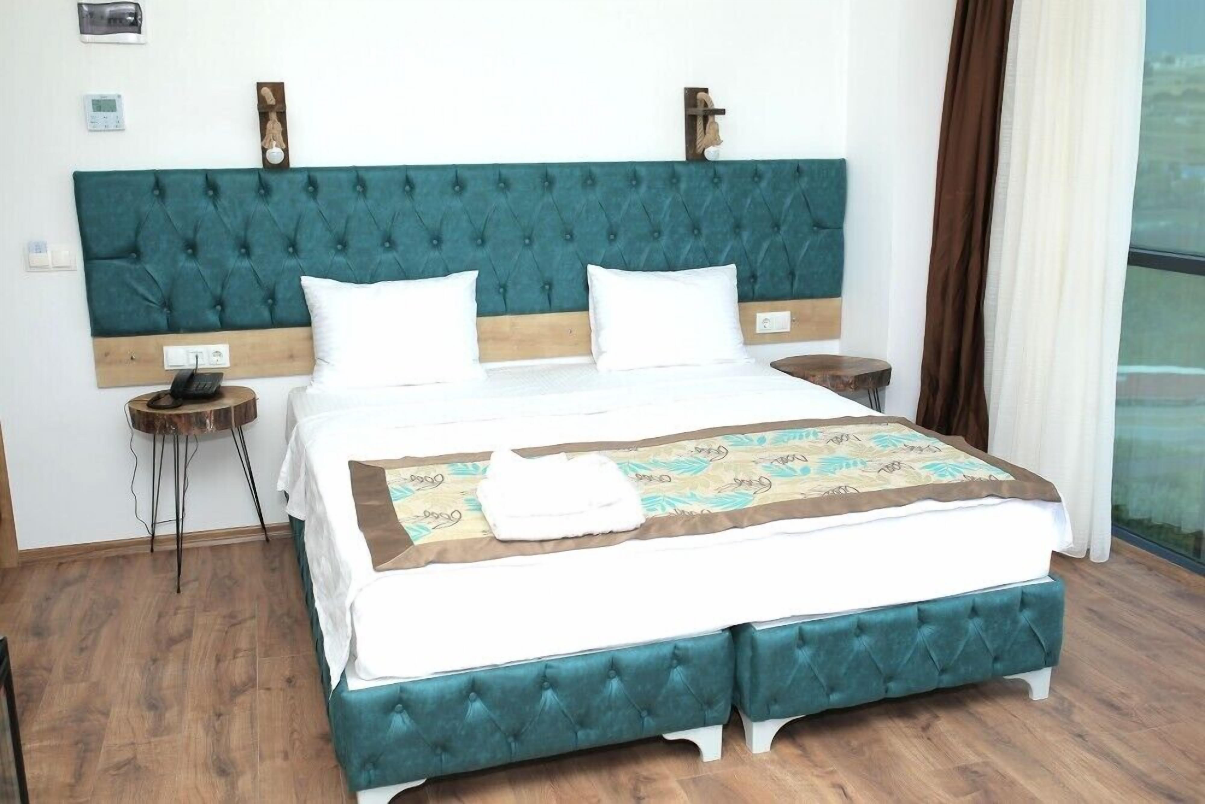 A neatly made bed with a teal headboard, white bedding, and a decorative throw.