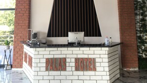 Una recepción con un cartel que dice "PALAS HOTEL" y un diseño moderno con techo inclinado y detalles de ladrillo.