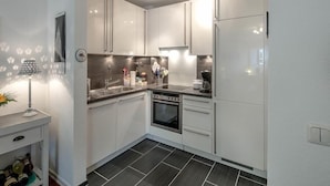 A modern kitchen with white cabinets, a built-in oven, and a refrigerator. - Residenz Barke App 10 (Scharbeutz)