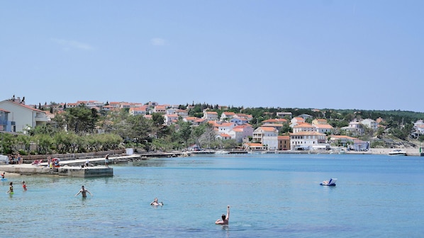 A coastal town with buildings, a pier, and people swimming in the water. - Apartment Sonja 2 (Dobrinj)