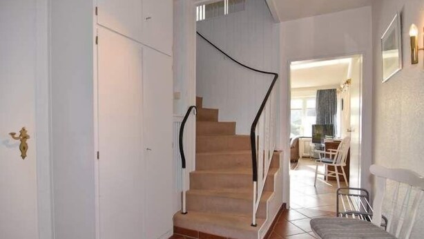 Eine Treppe mit schwarzer Handläufung, die zu einer Zwischenebene führt.