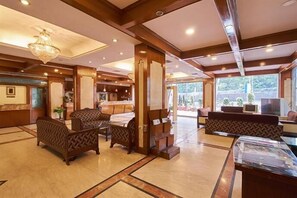 A spacious lobby with wooden furniture, a reception desk, and a chandelier.