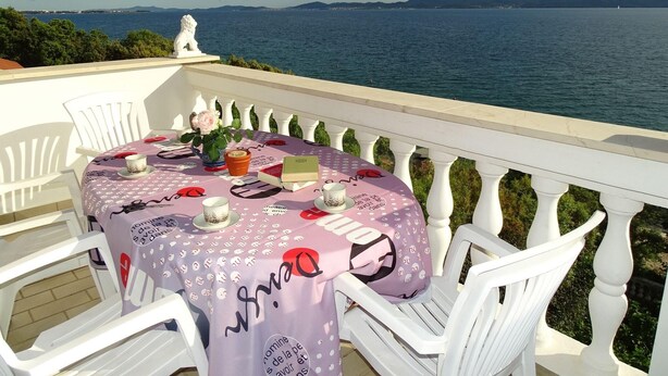A table set on a balcony with a view of the sea and mountains. - Apartment Vlahov (Barilovic)