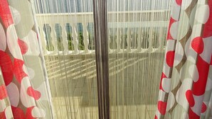 A window with vertical blinds and a view of a balcony with railings. - Apartment Vlahov (Barilovic)