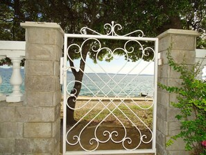 A wrought iron gate with a view of a body of water and a tree in the background. - Apartment Vlahov (Barilovic)