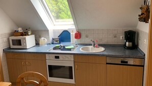 A compact kitchen with a microwave, toaster, sink, and coffee maker. - Ferienhaus Hirschrudel - Ferienwohnung 3 (Katzow)
