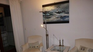 Ein Wohnzimmer mit zwei Sesseln, einem kleinen Tisch und einem Gemälde eines Leuchtturms.
