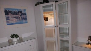Ein Schlafzimmer mit einem weißen Kleiderschrank, einem Nachttisch mit Lampe und einem Bild an der Wand.
