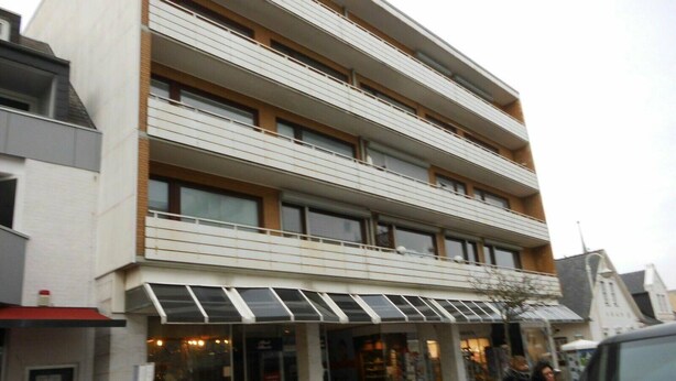 Ein mehrstöckiges Gebäude mit einer glatten Fassade, großen Fenstern und einem überdachten Eingangsbereich.