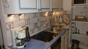 Eine Küche mit weißen Schränken, einer Edelstahlspüle, einer Kaffeemaschine und einer Mikrowelle.