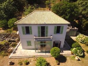 A two-story house with a tiled roof, green shutters, and a small balcony. - Independent villa with private garden in Cap Corse, between sea and forest (CAGNANO)