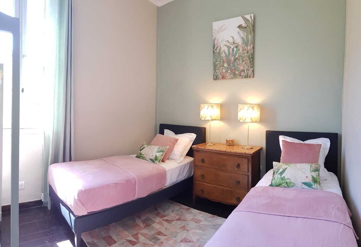 Ein Schlafzimmer mit zwei Betten, einem Nachttisch mit Lampen und einem Bild an der Wand.