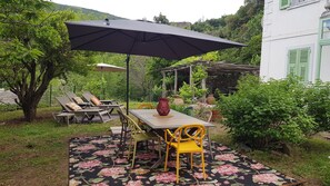 An outdoor patio with a table, chairs, and a large umbrella. - Independent villa with private garden in Cap Corse, between sea and forest (CAGNANO)