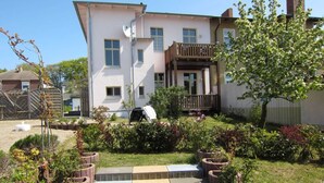 A two-story house with a covered porch and a small garden with steps leading to the front door.