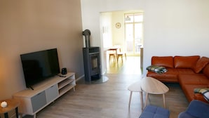 A living room with a TV, a fireplace, a sofa, and a dining area in the background.