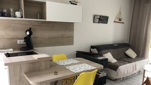 Un espacio habitable moderno y compacto con kitchenette, comedor y sofá.