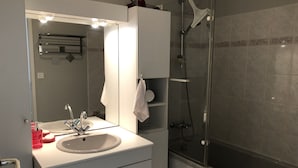 Un baño moderno con lavamanos blanco, espejo y cabina de ducha de vidrio.