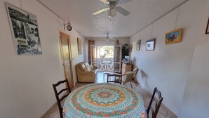 A dining area with a round table covered by a floral tablecloth, surrounded by wooden chairs. - Quiet T3 Apartment with Terrace and Equipped Kitchen, 300m from the Beach in Collioure (Collioure)