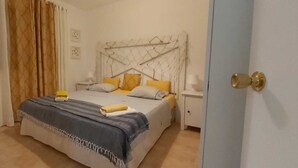 Une chambre à coucher avec un lit, des tables de chevet, une armoire et une porte.