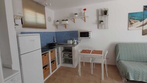 Une cuisine compacte équipée d’un réfrigérateur, d’un four à micro-ondes et d’un petit coin repas avec une table et des chaises.
