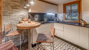 Una cocina moderna con una pared de piedra, una mesa redonda de comedor y cuatro sillas de mimbre.