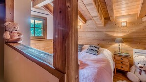 Una habitación de madera acogedora con una cama, una mesita de noche, una lámpara y dos osos de peluche.