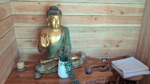 En træfigur af Buddha på en træbænk i et rum med trævægge.