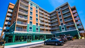 Un hôtel à plusieurs étages doté de balcons, d’une façade vitrée et d’un espace de stationnement.