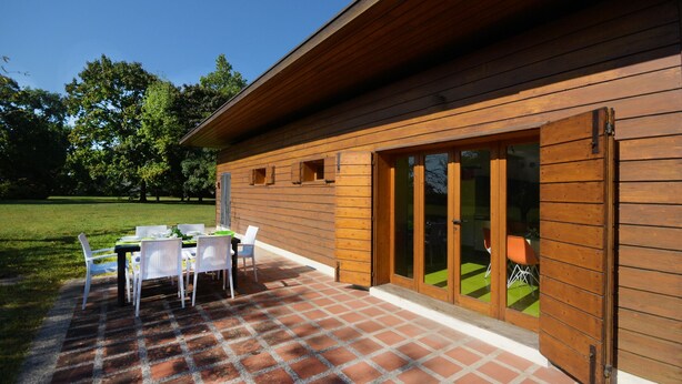 A wooden cabin with a patio area featuring a table and chairs. - Design cottage Treviso - the house in the park (Treviso)