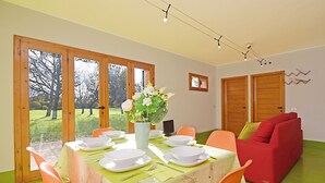 A dining area with a table set for four, surrounded by orange chairs, a red sofa, and a vase with flowers. - Design cottage Treviso - the house in the park (Treviso)