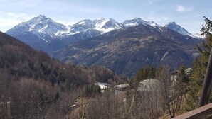 A mountain landscape with snow-capped peaks and a valley with sparse trees. - Sauze D'oulx - Italie - Joli Studio Avec une Superbe vue sur les Montagnes (Sauze d'Oulx)