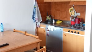 A compact kitchen with wooden cabinets, a stainless steel stove, and a dishwasher. - Sauze D'oulx - Italie - Joli Studio Avec une Superbe vue sur les Montagnes (Sauze d'Oulx)