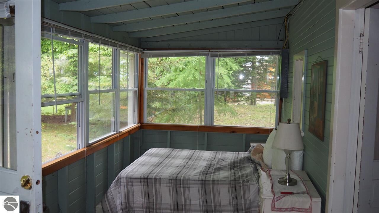 Una habitación con cama, lámpara y ventana con vistas a un jardín.