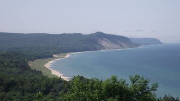 Eine Küstenlandschaft mit Strand, bewaldeten Hügeln und freiem Blick auf den Ozean.