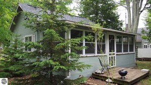 Une maison de plain-pied avec un porche, une petite terrasse et un barbecue.