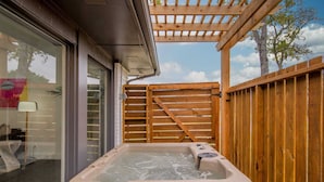 Ein Whirlpool in einem überdachten Außenbereich mit Holzzaun und einer darüberliegenden Pergola.