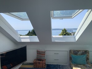 A room with skylights, a television, a chest of drawers, and a patterned headboard. - Seafacing villa in Torquay with 2 suites and a heated swimming pool (Torquay)