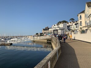 A waterfront promenade with a white bridge, calm water, and buildings with balconies. - Seafacing villa in Torquay with 2 suites and a heated swimming pool (Torquay)
