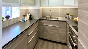A modern kitchen with a built-in sink, stainless steel appliances, and light wood cabinetry. - Presqu'île du Capelan | Parking |Climatized |Preserved seaside |Calm assured (Bandol)