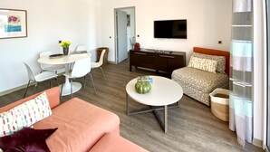 A modern hotel room with a sofa, a small round table, a TV, a bed, and a window with curtains. - Presqu'île du Capelan | Parking |Climatized |Preserved seaside |Calm assured (Bandol)
