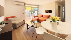 A modern living room with a sofa, a dining table, and a TV. - Presqu'île du Capelan | Parking |Climatized |Preserved seaside |Calm assured (Bandol)